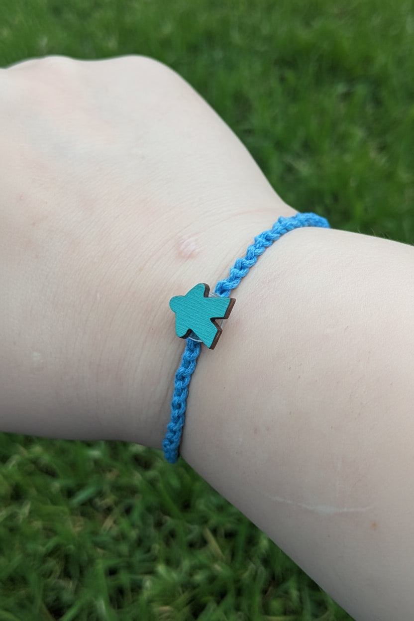 Blue bracelet with a star charm on a wrist against grass background